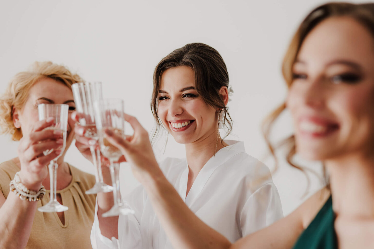 Panna młoda pije szampana z mamą oraz świadkową w czasie przygotowań do ślubu