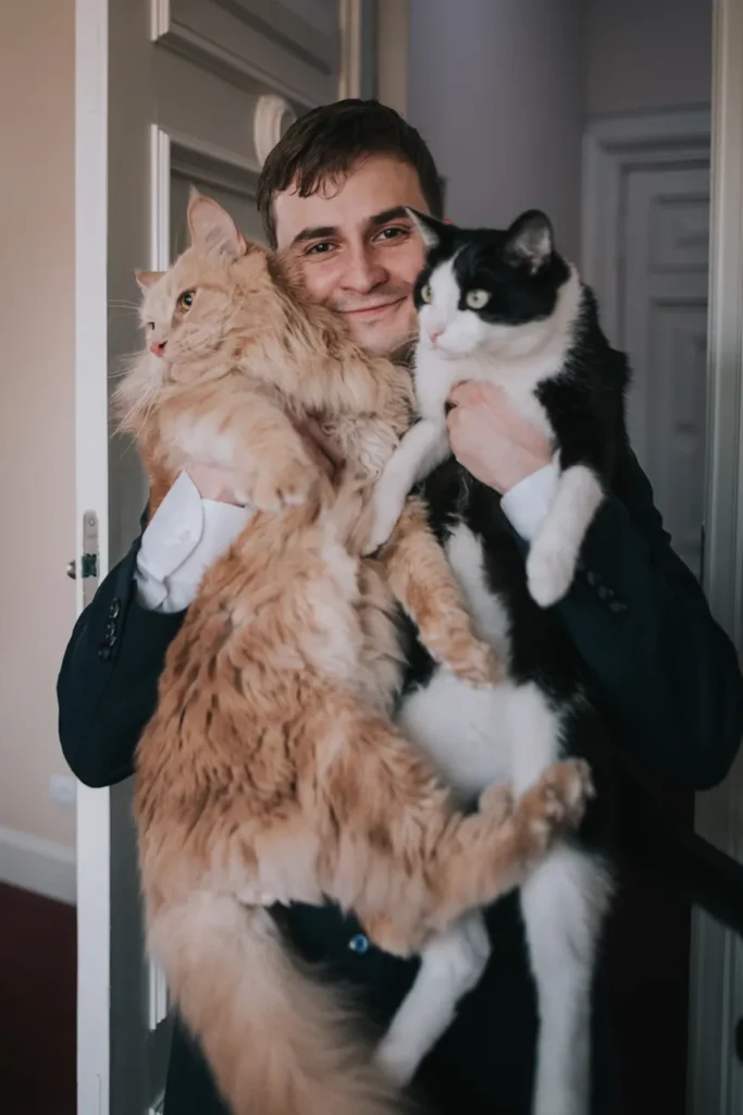 Pan młody przytulający swoje koty uchwycony w czasie sesji zdjęciowej z kotami
