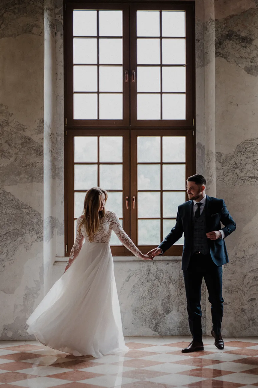 Para młoda pozująca przy oknie w opactwie cystersów w Lubiążu w czasie sesji ślubnej