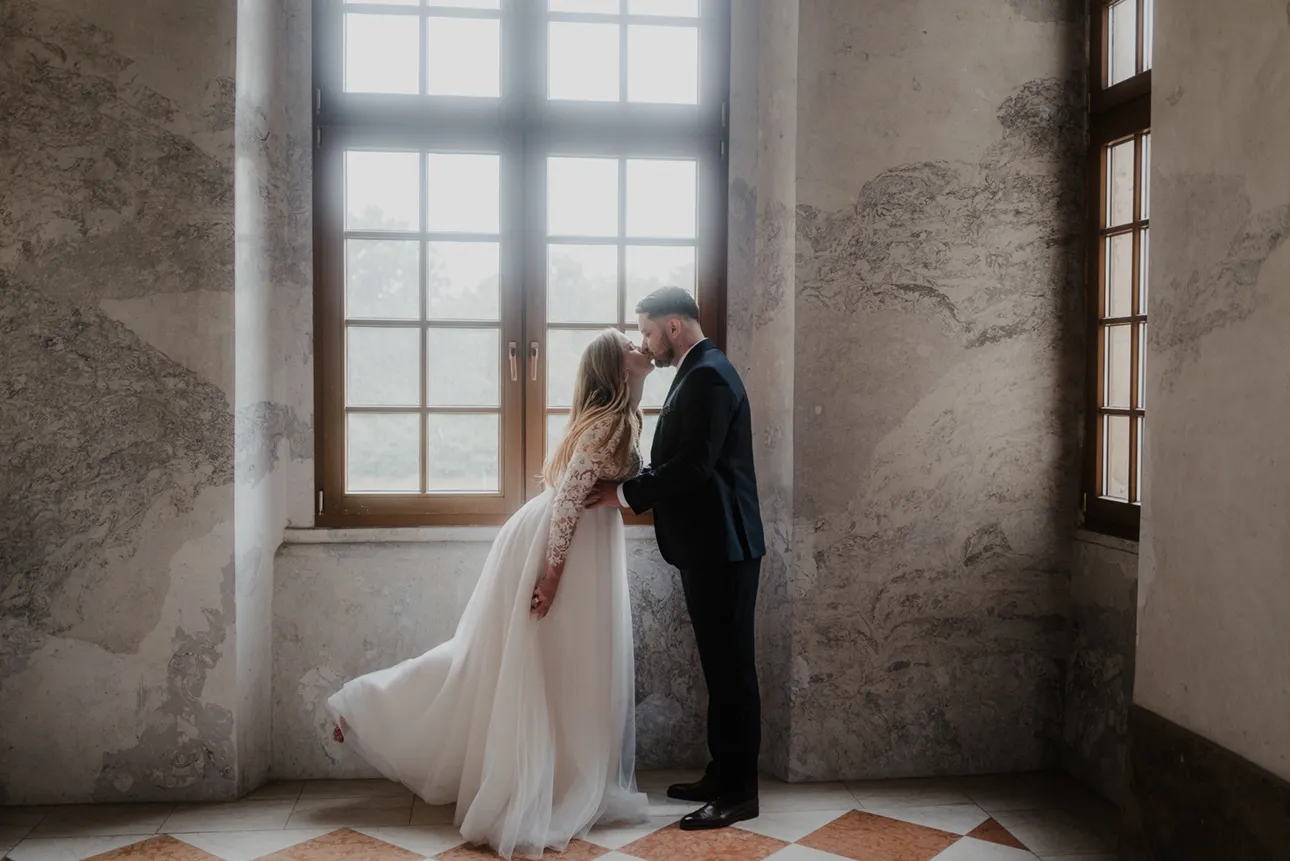 Para młoda całuje się na tle okna w opactwie cystersów w Lubiążu
