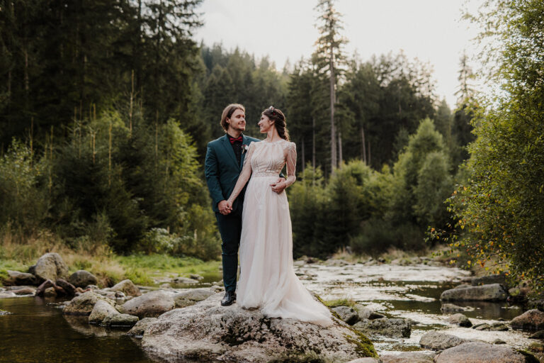 Para młoda stojąca na środku potoku niedaleko wodospadu