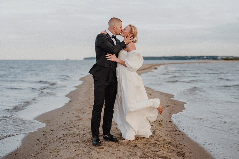 Całująca się na plaży para młoda podczas sesji ślubnej