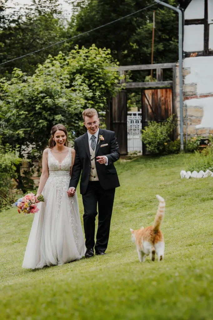 Spacerująca po ogrodzie para młoda spotyka kotka podczas slow wedding w Polnej Zdrój