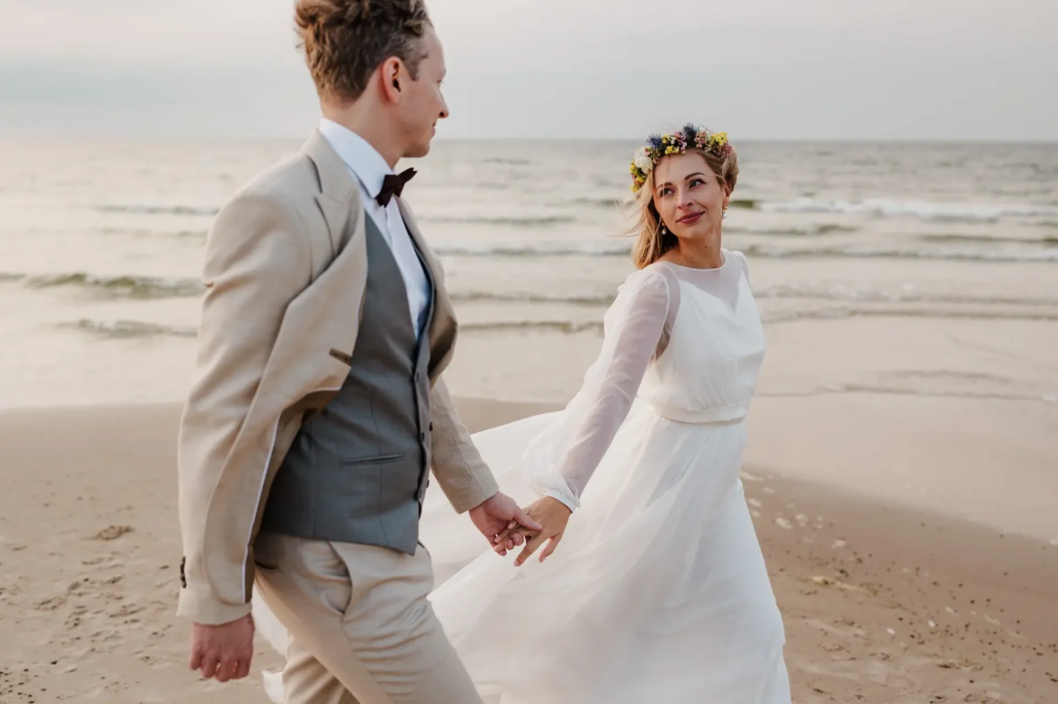 Przykład naturalnej fotografii ślubnej na której para młoda patrzy sobie w oczy spacerując brzegiem morza