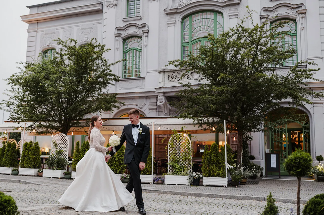 Przykładowe zdjęcie z mojej oferty fotografii ślubnej, na którym uśmiechnięta para młoda spaceruje trzymając się za ręce